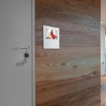 Un videocitofono bianco montato su parete in legno