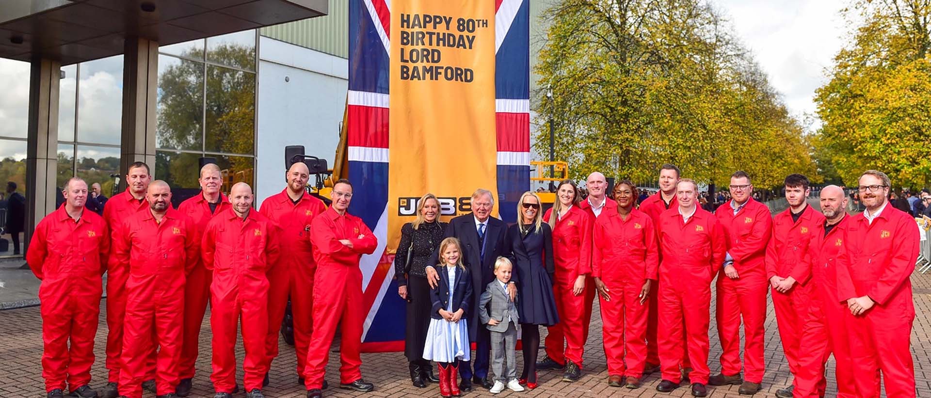 Jcb Lord Bamford attorniato dai famigliari e da alcuni dipendenti